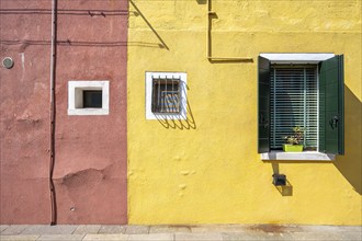 Red and yellow house facade with windows, colourful houses on the island of Burano, Venice, Veneto,