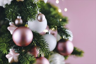 Close up of decorated Christmas tree with white seasonal and pink tree ornaments like baubles and