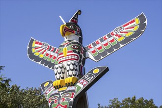 Colourful wooden carved Canadian totem pole showing eagle against blue sky