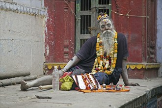 Handicapped Sadhu selling offerings for temple in Varanasi, Uttar Pradesh, India, Asia