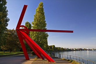 Bright red sculpture made of steel profiles L'Allumé by Mark di Suvero, Rhine bank, pointing