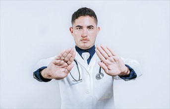 Doctor making a stop gesture with palms on white background. Latin doctor making a stop gesture