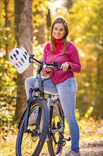 Woman sitting on Ebike through autumn forest, Black Forest, Gechingen, Germany, Europe