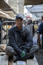 Worker sitting on planks, Osh Bazaar, Bishkek, Kyrgyzstan, Asia