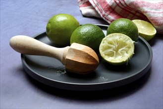 Limes with citrus squeezer on plate