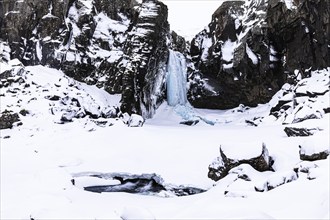 Frozen waterfall, Folaldafoss, snowy rock face and snowy landscape, Sudausturland, Iceland, Europe