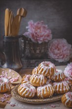 Muffins with pink icing in front of peonies (Paeonia)