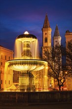 Fountain in the Geschwister-Scholl-Platz and St. Ludwig's Church (Ludwigskirche) in the evening.