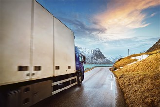 Truck on road in Norwegian fjord on sunset. Lofoten islands, Norway. Motion blur