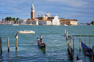 VENICE, ITALY, JUNE 27, 2018: Gondolier with client tourists in gondola in lagoon of Venice by