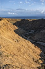 Canyon runs through a landscape of eroded hills at sunrise, Badlands, Issyk Kul Lake in the