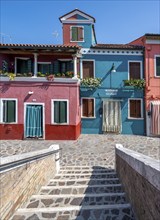 Bridge over a canal, red and turquoise houses with flowers, colourful house facades, alleys on the