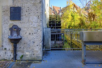 Commemorative plaque Eduard Mörike, drinking water basin and historic mill wheel at the