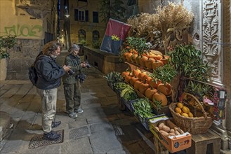 Tourists photographing a fruit shop in the evening in the historic centre, Genoa, Italy, Europe