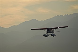 A Beaver De Havilland bush plane with floats against the backdrop of the Chugach Mountains on