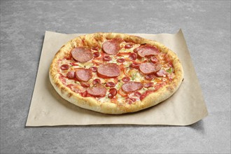 Top view of pizza with sausage and colorful bell pepper on parchment