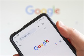 Hand holding mobile phone with Google logo of computer hardware software and search engine