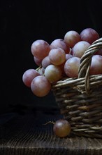 Red grape vine (Vitis vinifera) in baskets against a dark background