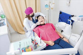 Stomatologist woman cleaning a patient's teeth, High angle of stomatologist cleaning woman's teeth,