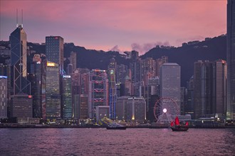 HONG KONG, CHINA, MAY 1, 2018: Tourist junk boat ferry with red sails and Hong Kong skyline