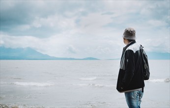 Rear view of tourist looking at a lake with volcanoes. Explorer person looking at a lake on a sunny