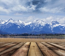 Wooden planks floor with Bavarian Alps countryside lake landscape in background. Bavaria, Germany,