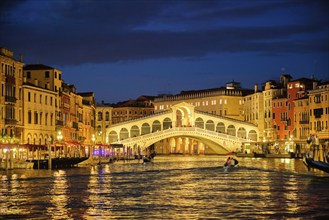 Famous Venetian tourist landmark Rialto bridge (Ponte di Rialto) over Grand Canal illuminated at