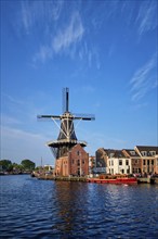 Harlem cityscape, landmark windmill De Adriaan on Spaarne river with boats. Harlem, Netherlands