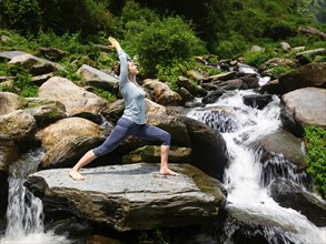 Yoga outdoors, sporty fit woman doing Ashtanga Vinyasa Yoga asana Virabhadrasana 1 Warrior pose