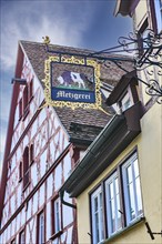 Historical sign of guild butcher craft butchery, in the background historical half-timbered house,