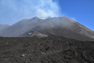 Hiking group below the smoking crater of the volcano Etna, Province of Catania, Sicily, Italy,