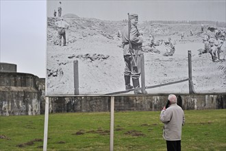 Visitors with audio guide looking at pictures of prisoners at Fort Breendonk, Belgium, Europe