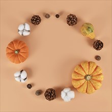 Seasonal autumn decoration like pumpkins and fir cones forming circle on beige background with