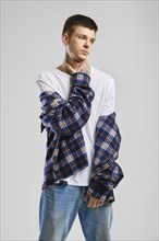 Young cocky man in checkered shirt and jeans touching his throat