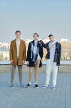 Three young men in autumn clothes are walking down the street