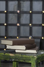 Tree big books on chair near old edison lamp mounted on wooden background