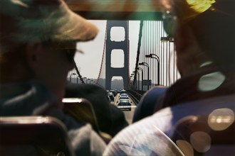 Passengers, tourists enjoying ride over the Golden Gate Bridge in a double-decker bus, coloured