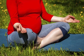 Pregnancy yoga exercise, pregnant woman doing asana Sukhasana easy yoga pose with chin mudra