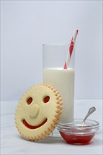 Pastry with smiley face and glass of milk