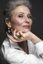 Portrait of a beautiful elderly woman in a white shirt with classic makeup and gray hair