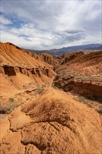 Eroded mountain landscape with sandstone cliffs, canyon with red and orange rock formations,