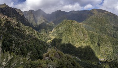 Densely overgrown steep mountains with rainbow, green mountain landscape, view from Miradouro dos