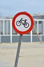 Red bicycle street warning sign on shore of Texel