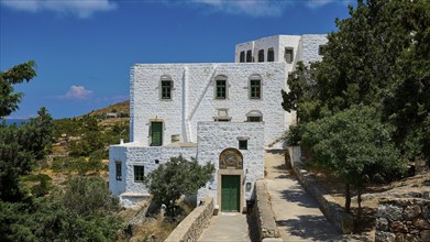 A white building with green windows and red roofs, decorated with a mosaic, in a Mediterranean