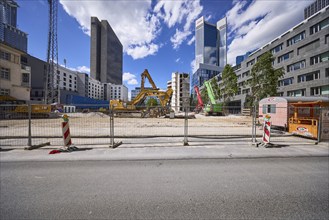 Construction site for the demolition of a building with construction fence and hydraulic excavators