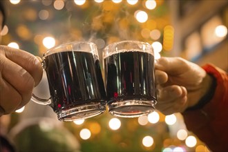 Two hands holding mulled wine cups in a festive night with lights, Lichternacht Fest, Nagold, Black