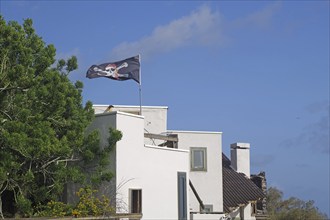 A white house with a waving pirate flag under a blue sky, San Andres, La Palma, Canary Islands,