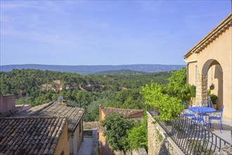 View over the roofs of the village to the ochre cliffs, Roussillon, Département Vaucluse, France,