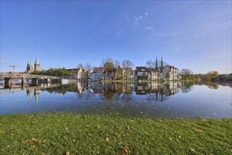 Long shot of the historic city centre, riverbank of the Trave, symmetrical reflections on the water