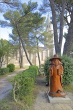 Wooden pilgrim in front of the baroque church Notre-Dame de Beauregard, wood carving, wooden